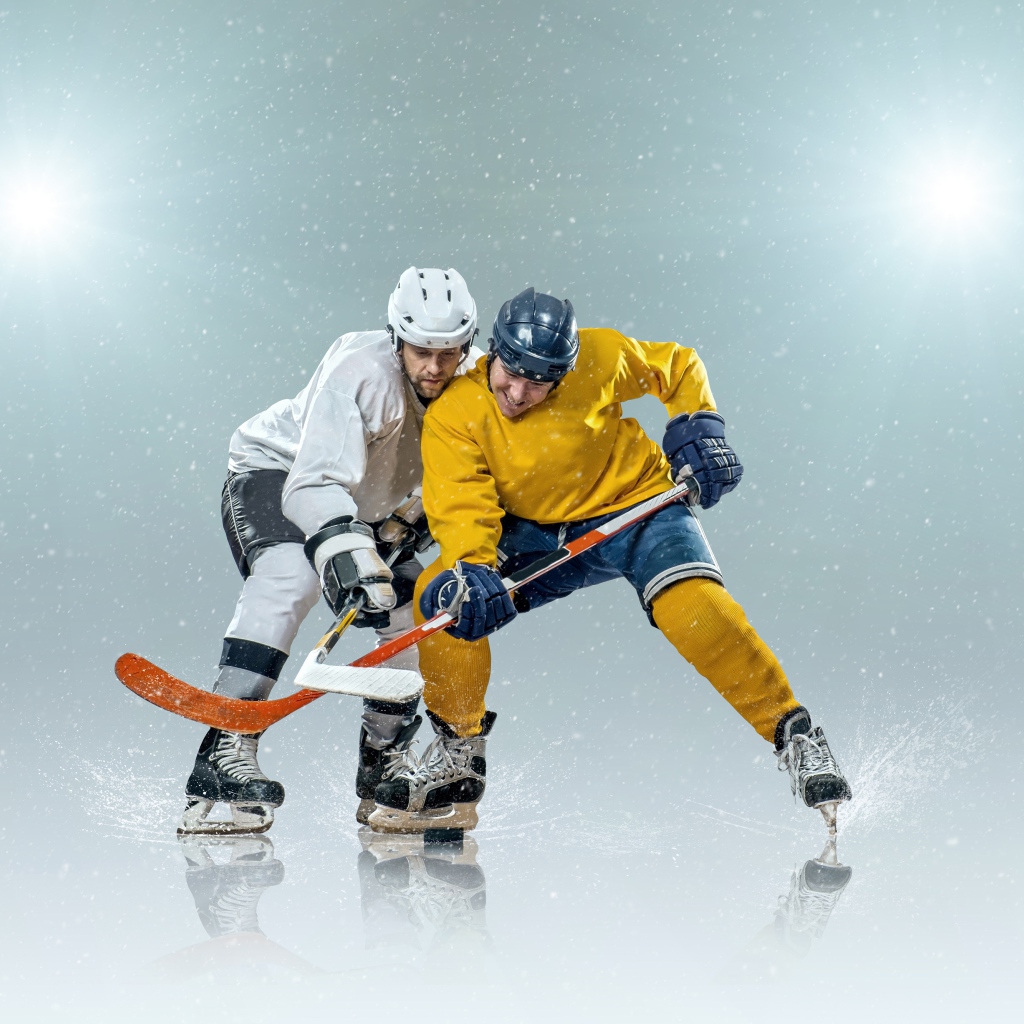 Два спортсмена хоккеиста на льду с клюшками