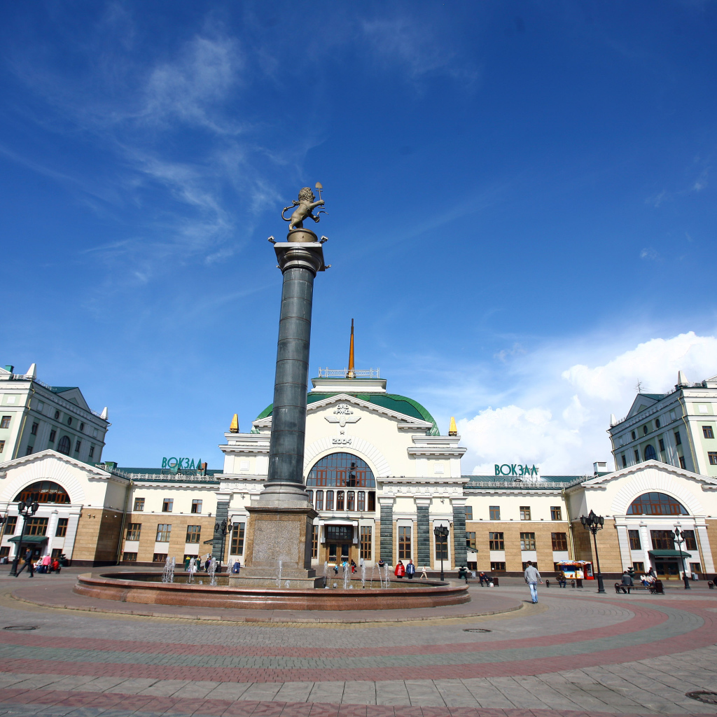 Памятник у здания железнодорожного вокзала под красивым голубым небом, Красноярск. Россия