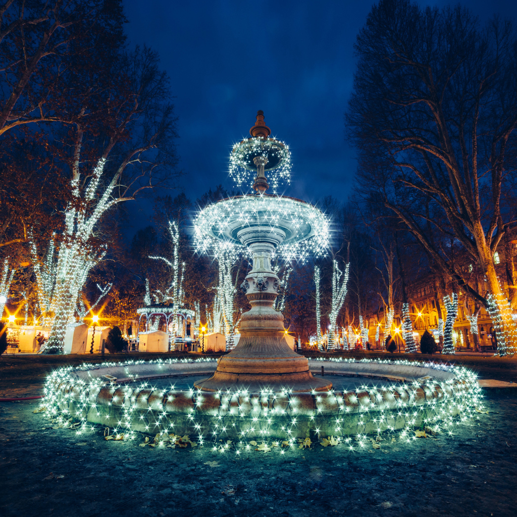 Красивый фонтан с гирляндами в городе вечером