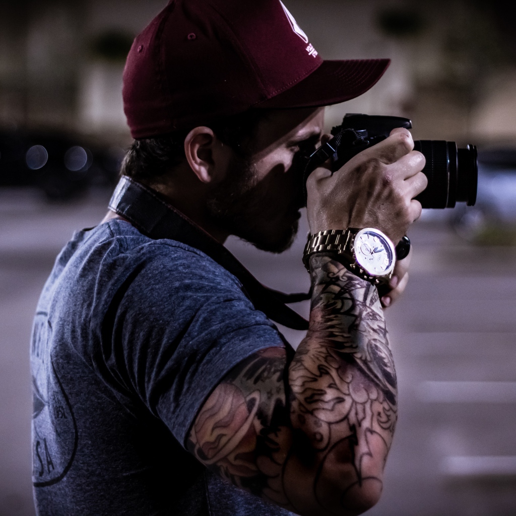 Мужчина с татуировкой на руке делает фото 