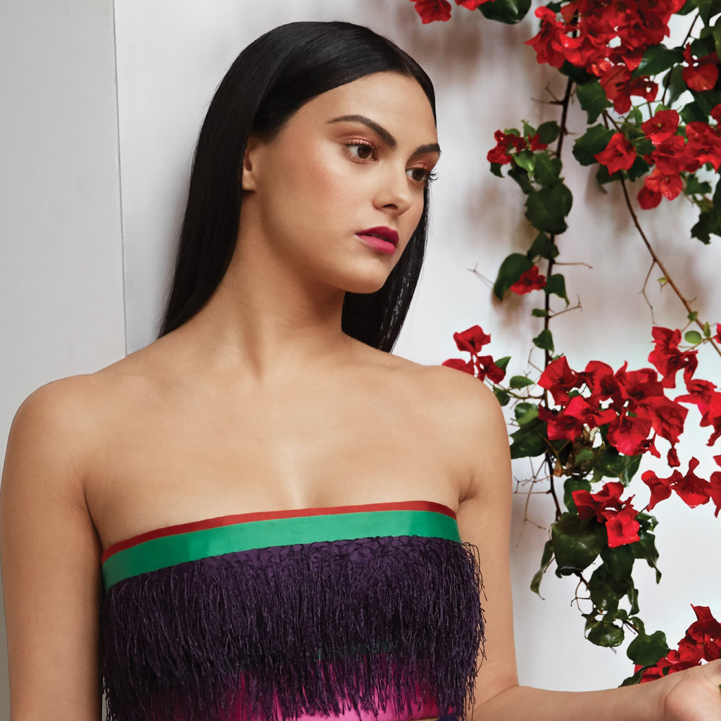 Актриса Камила Мендес стоит у стены с цветами