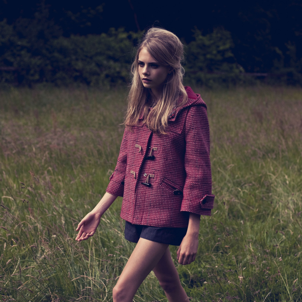 Актриса Кара Делевинь идет по траве в пальто 