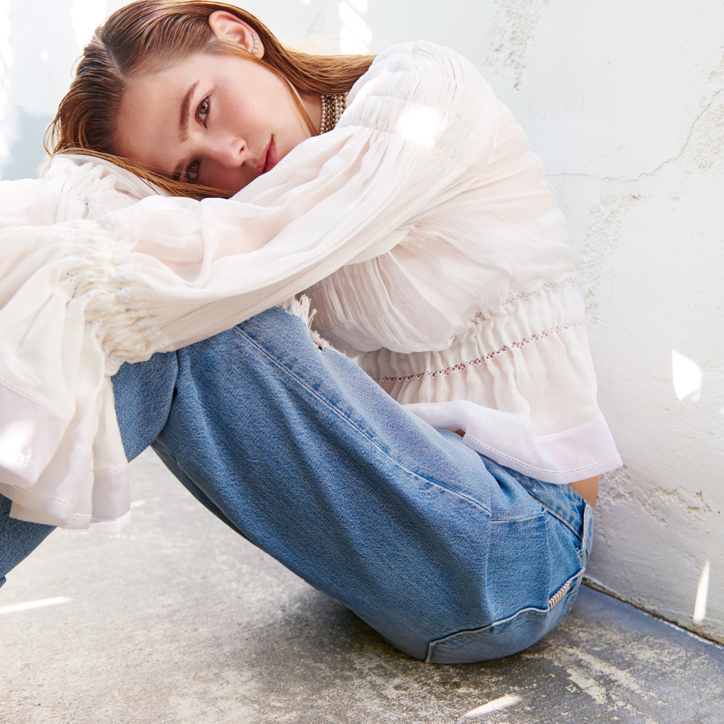 Актриса Зои Дойч сидит у стены