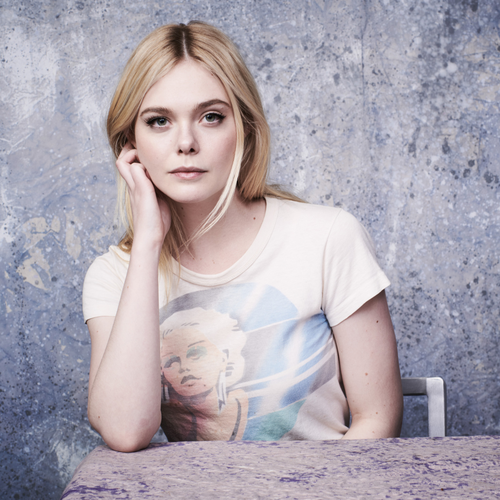 Красивая актриса Эль Фаннинг сидит за столом