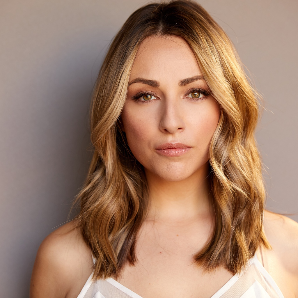 Красивая блондинка Никки Поснер на сером фоне 