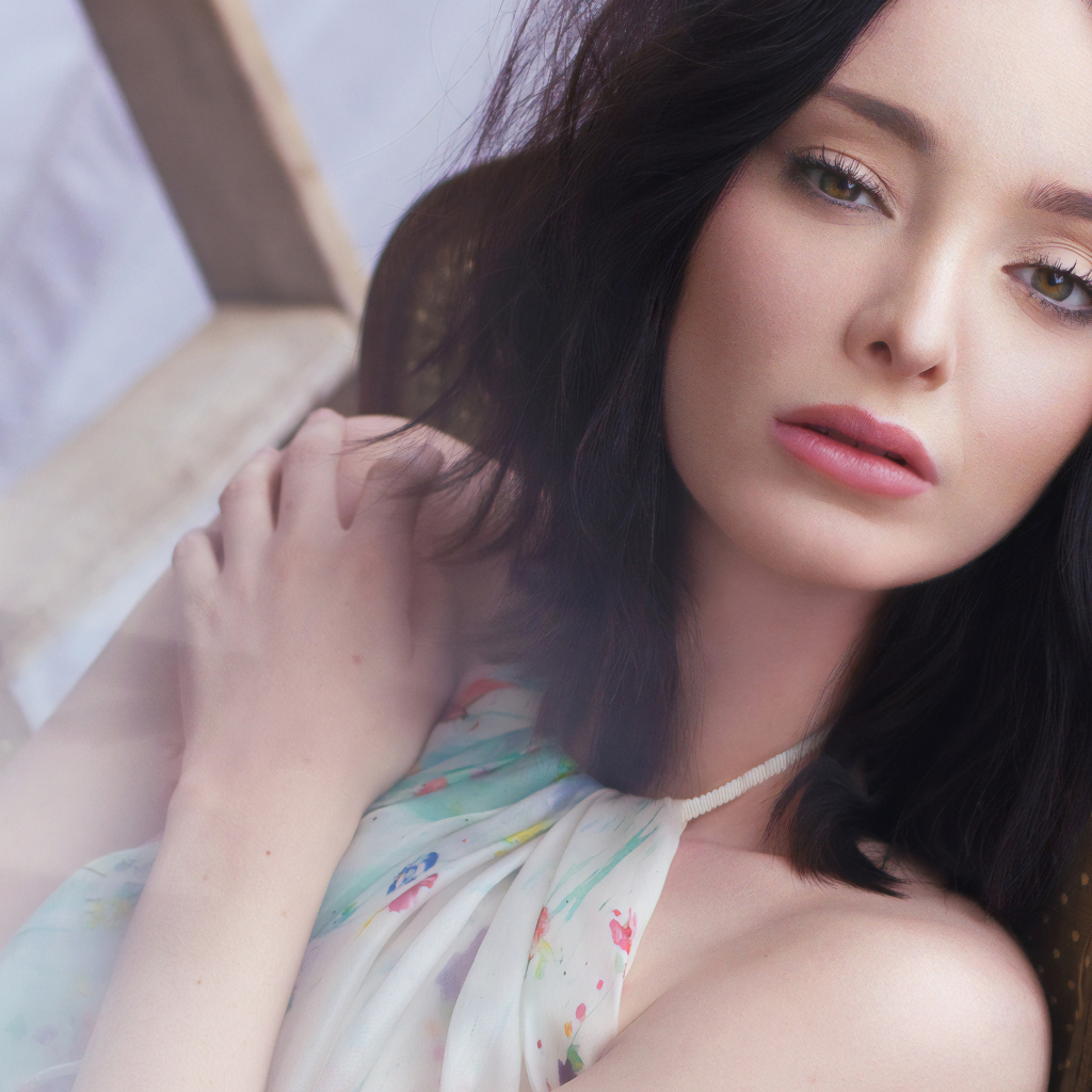 Красивая брюнетка, актриса Эмма Дюмон сидит на стуле 