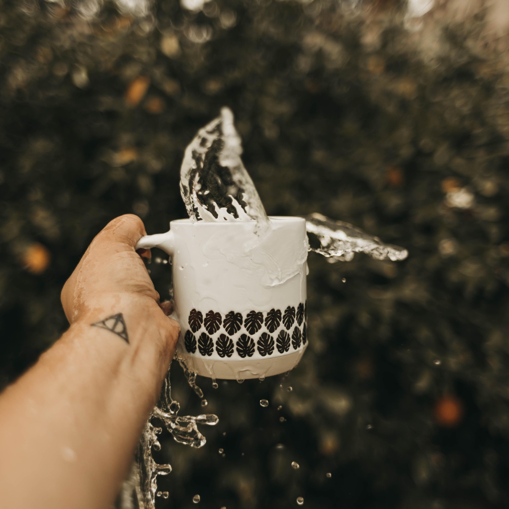 Чашка с водой в руке с татуировкой 