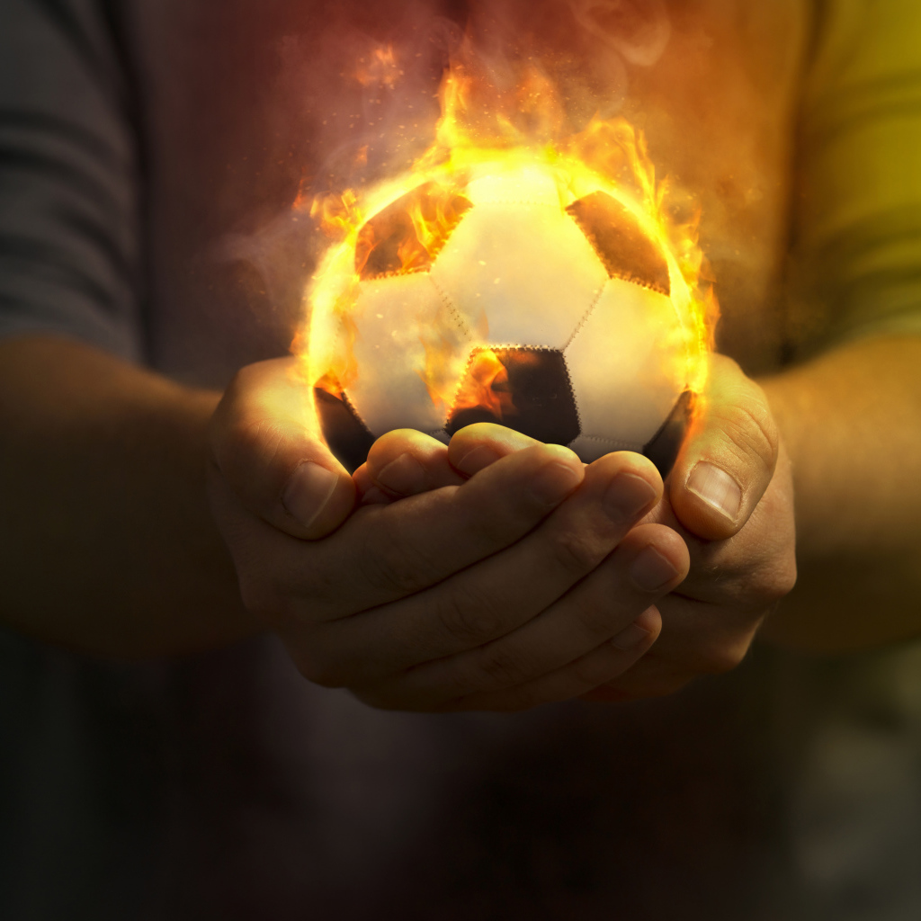 Огненный футбольный мяч в руках 