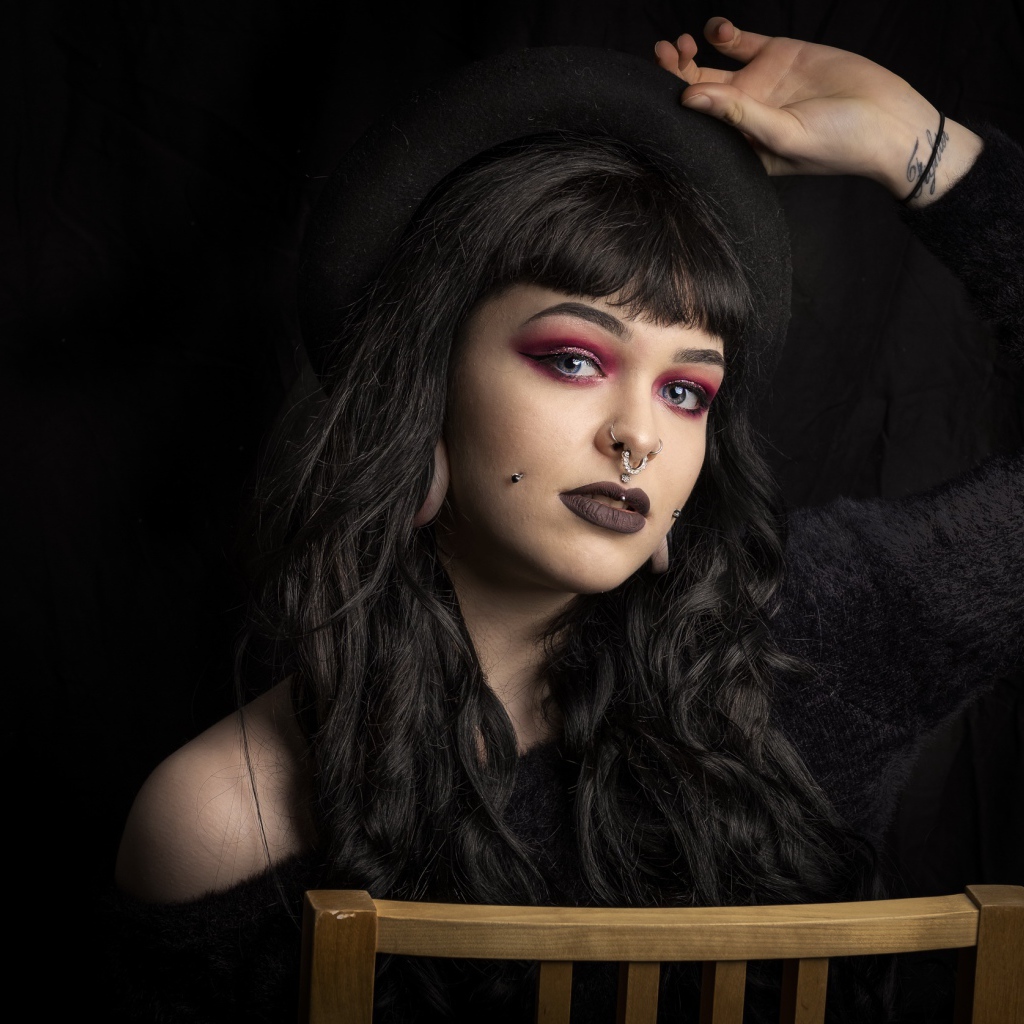 Девушка неформалка с черной шляпе с пирсингом на лице