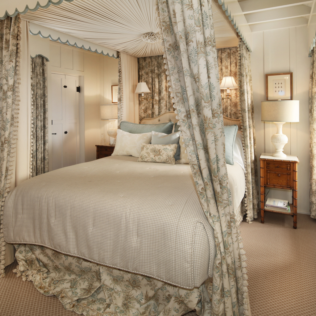 Высокая кровать с занавесками в спальной комнате в пастельных тонах 