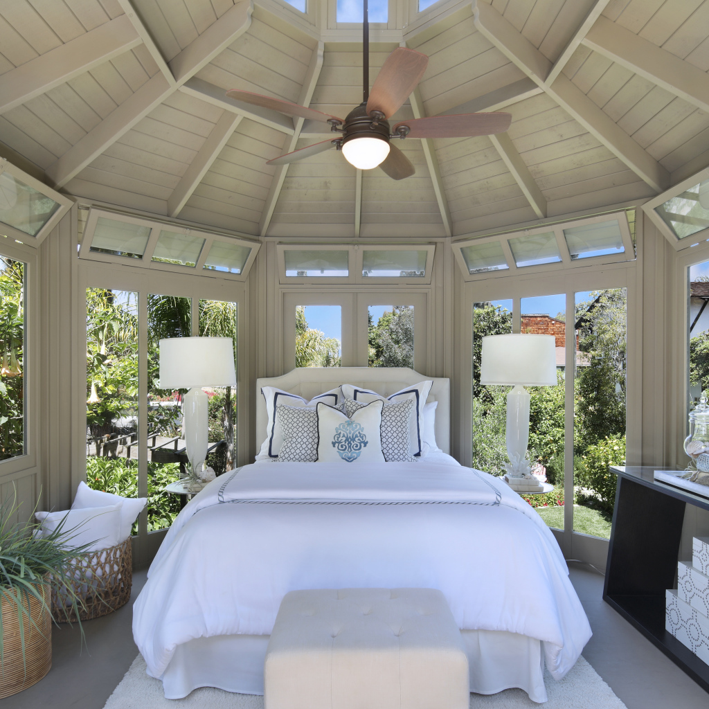 Большая спальная комната с окнами и белой кроватью 