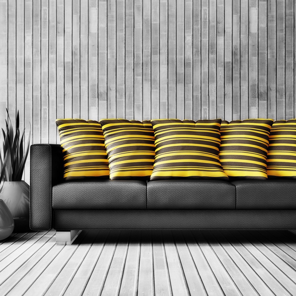 Большой черный кожаный диван с подушками у стены