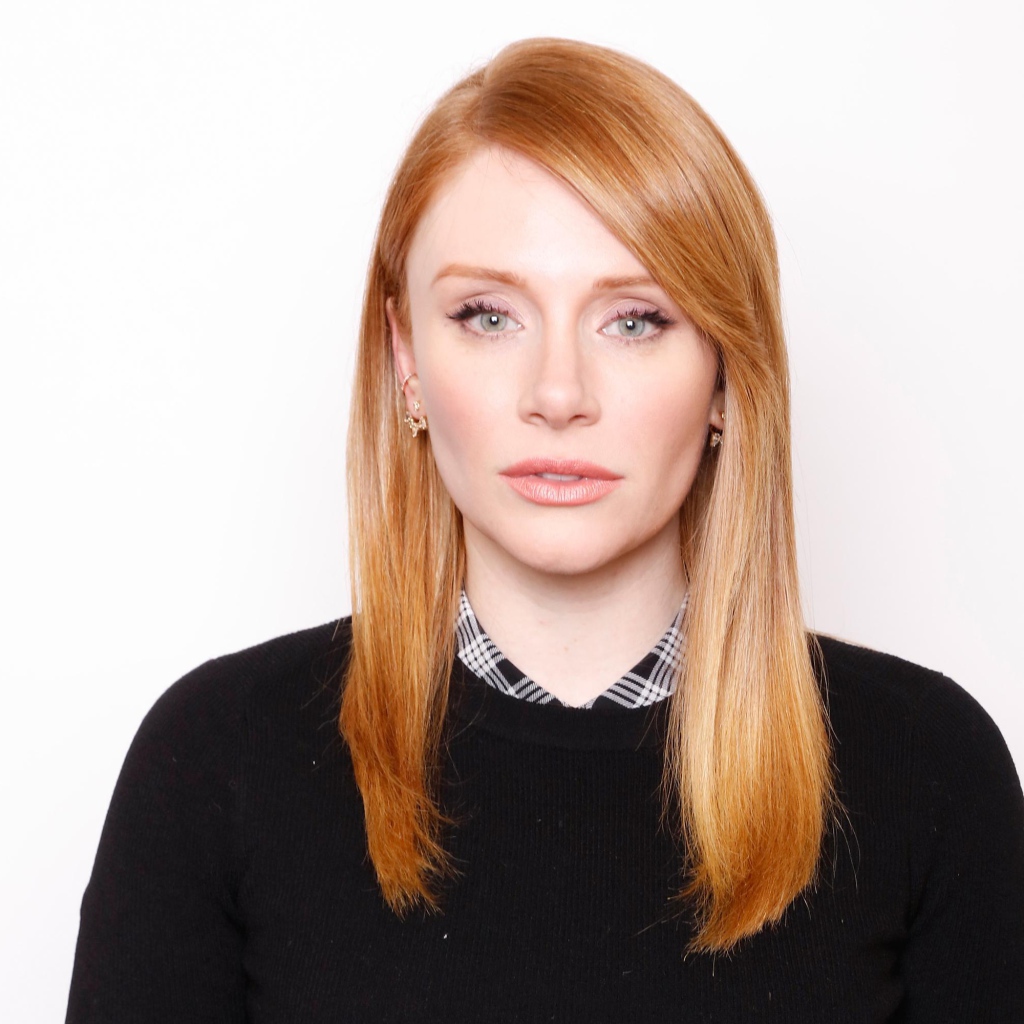 Рыжеволосая актриса Брайс Даллас Ховард в черном свитере на белом фоне