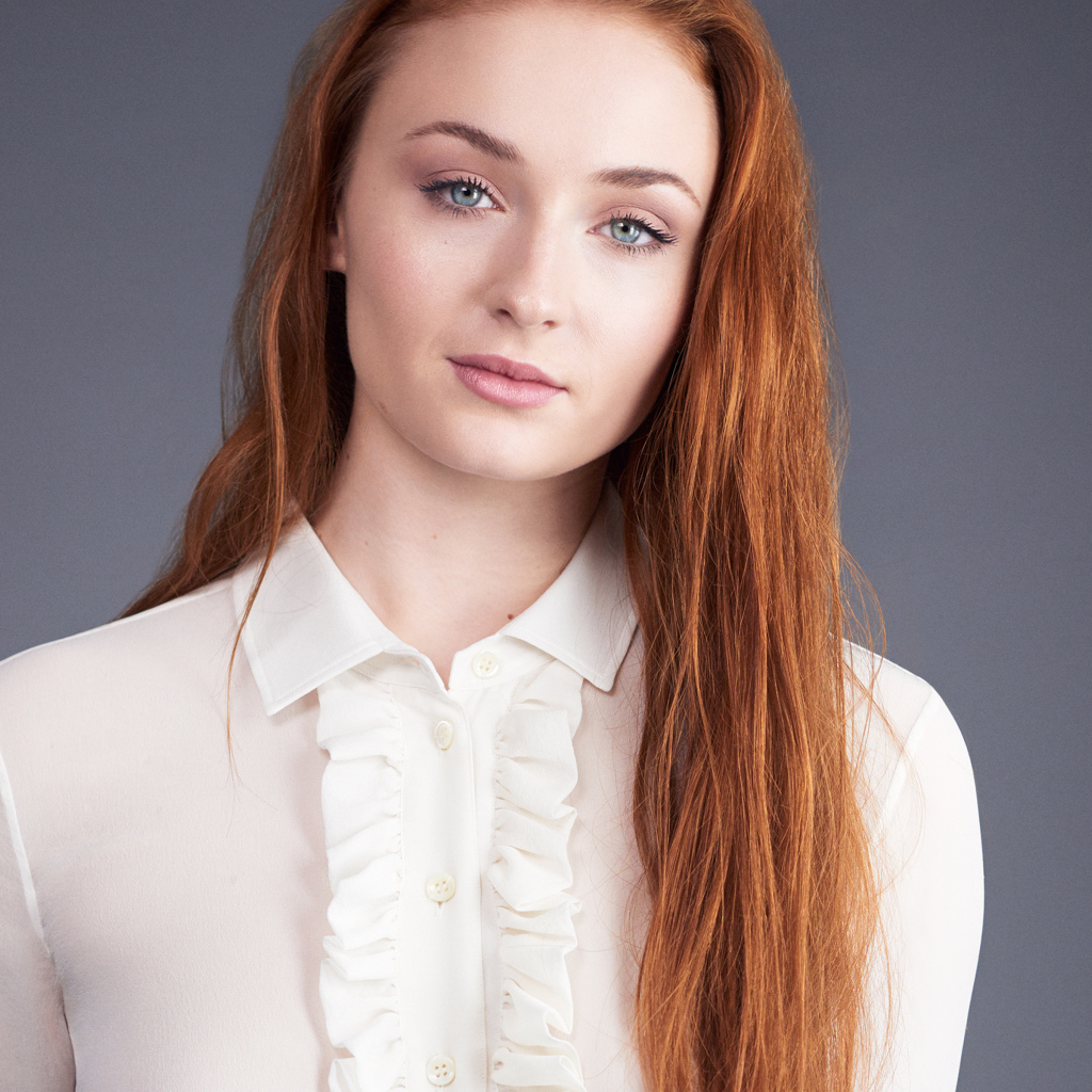 Рыжеволосая голубоглазая актриса Софи Тёрнер на сером фоне