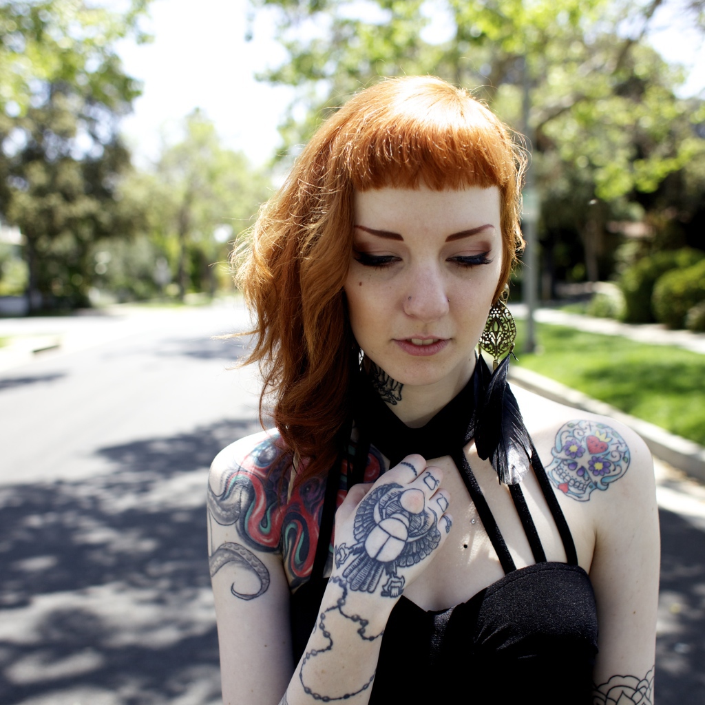 Рыжеволосая девушка неформалка с татуировками на теле