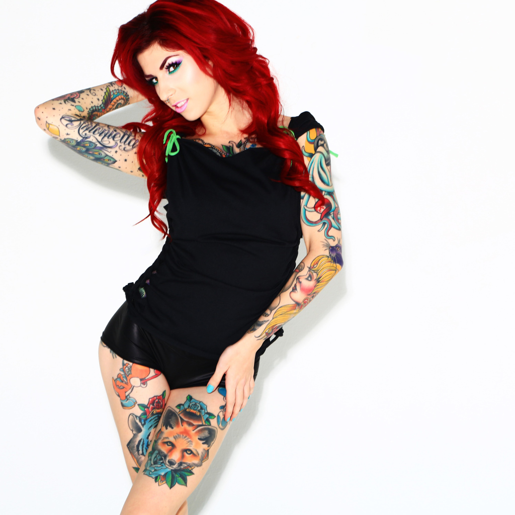 Рыжеволосая девушка с татуировками на теле на белом фоне