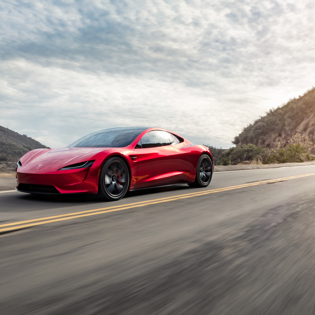 Красный автомобиль Tesla Roadster едет по трассе 