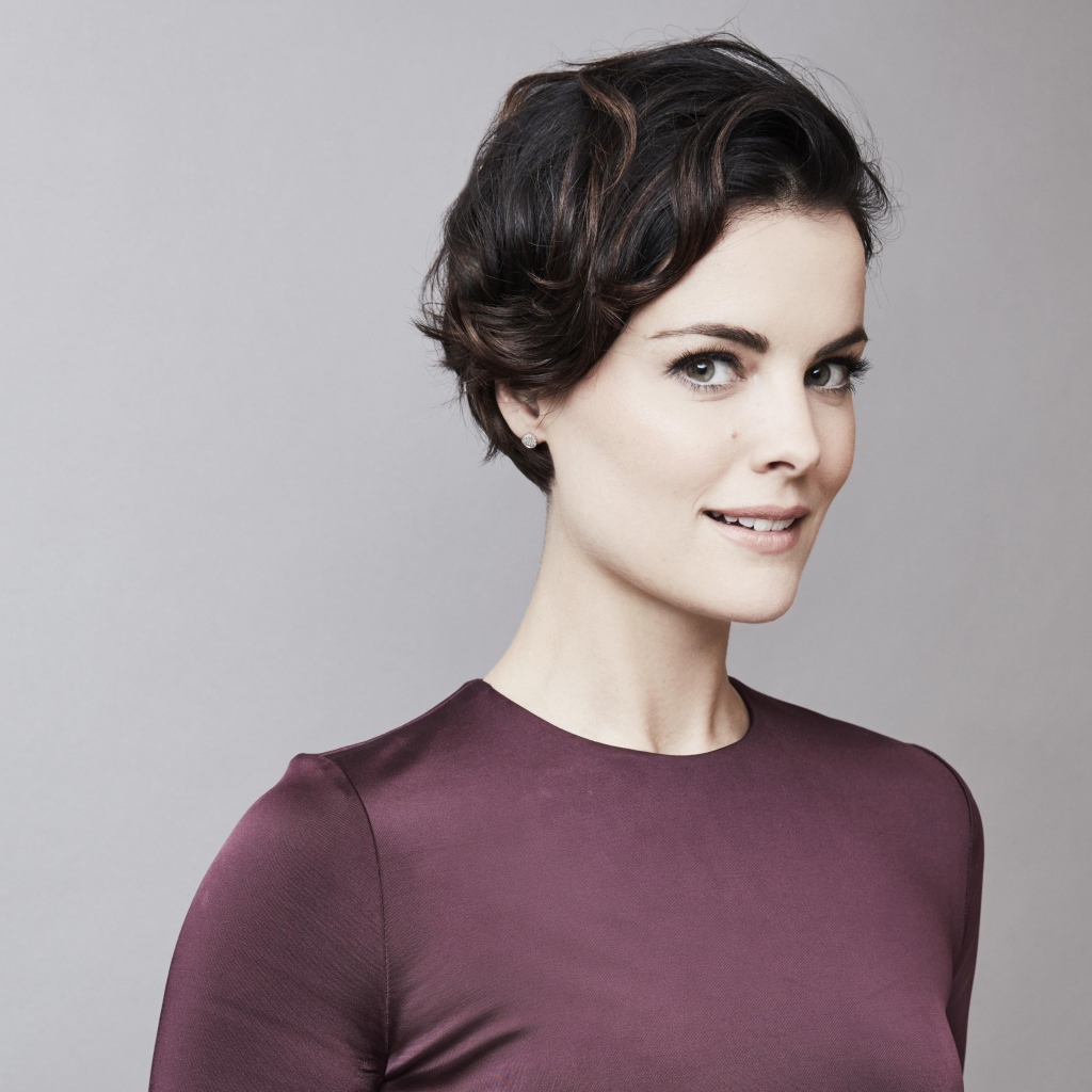 Улыбающаяся девушка, актриса Джейми Александр на сером фоне