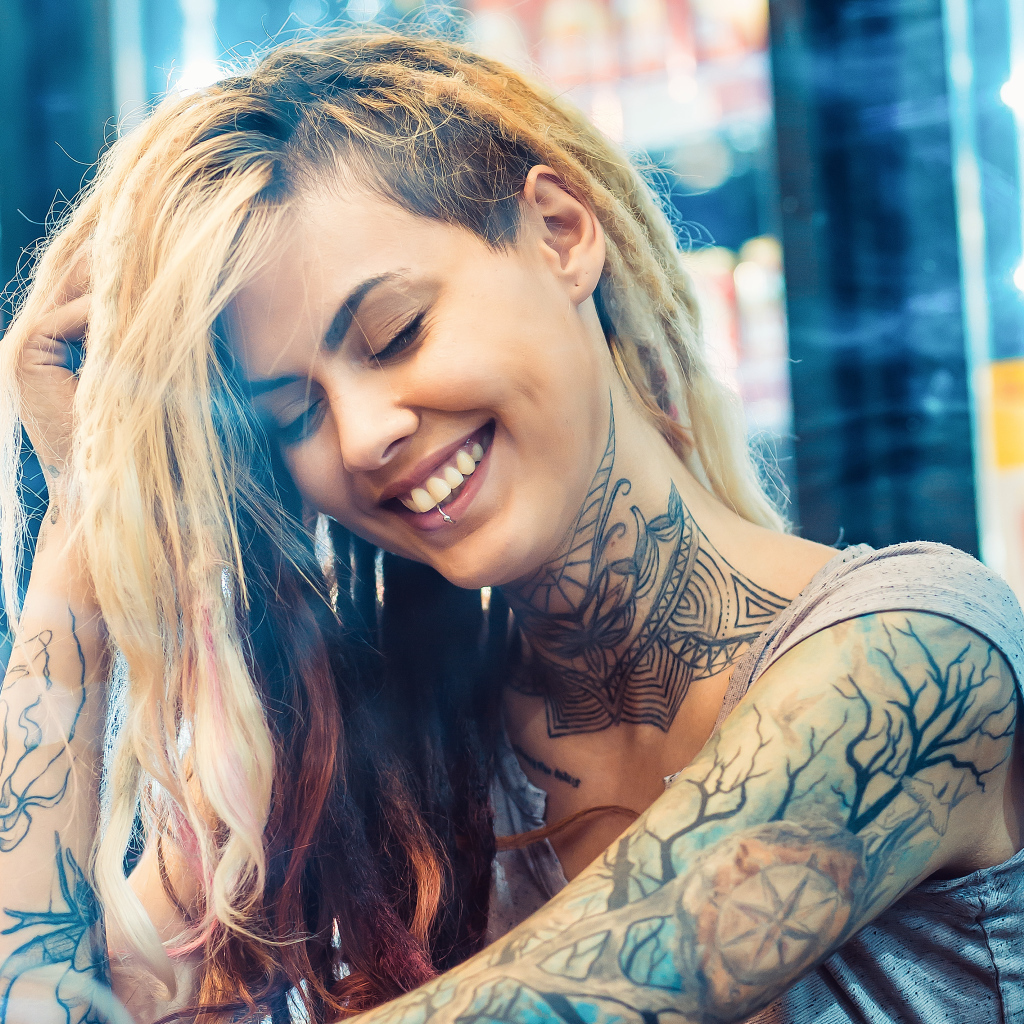 Улыбающаяся девушка с татуировками на теле