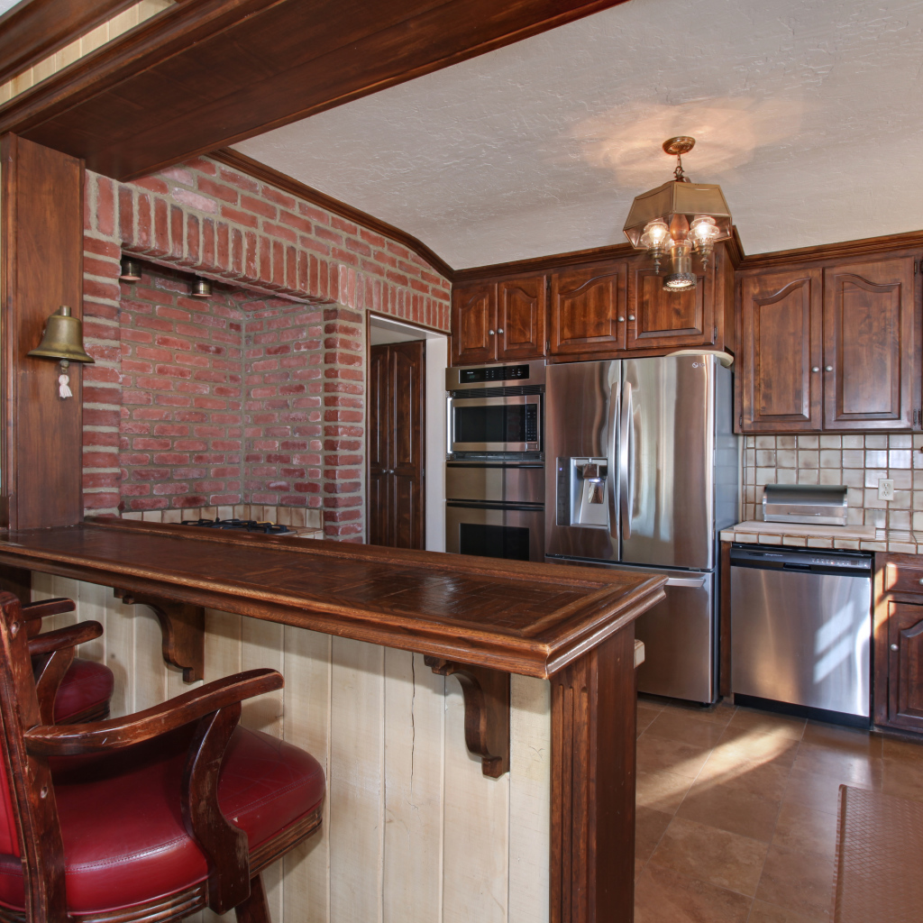 Просторная кухня с деревянной мебелью и кожаными стульями