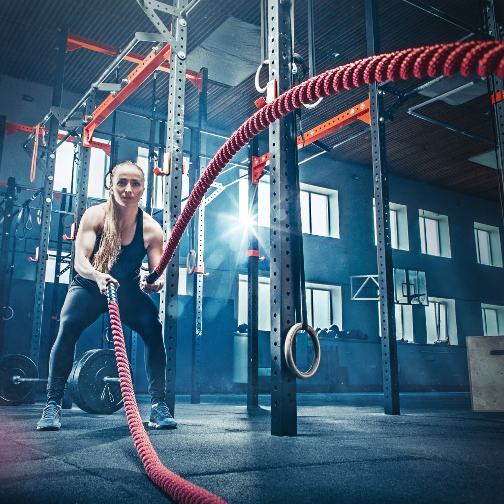 Девушка в спортзале занимается с канатами