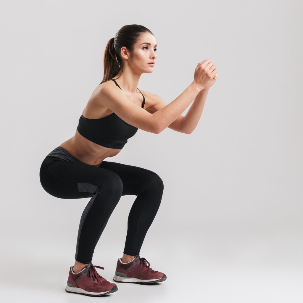 Девушка занимается гимнастикой на сером фоне