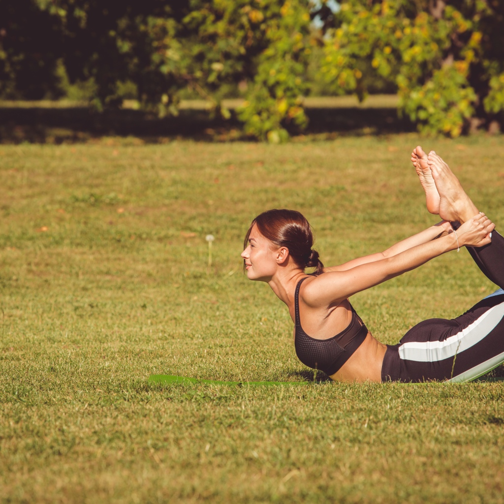 Девушка занимается гимнастикой на зеленой траве