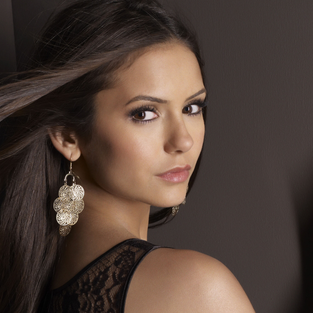 Ветер развивает волосы актрисы Нина Добрев на фоне стены