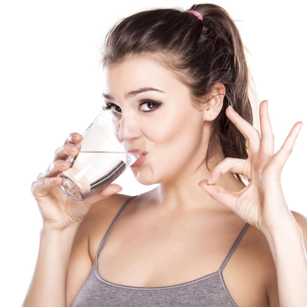 Young athletic girl drinks water from a glass