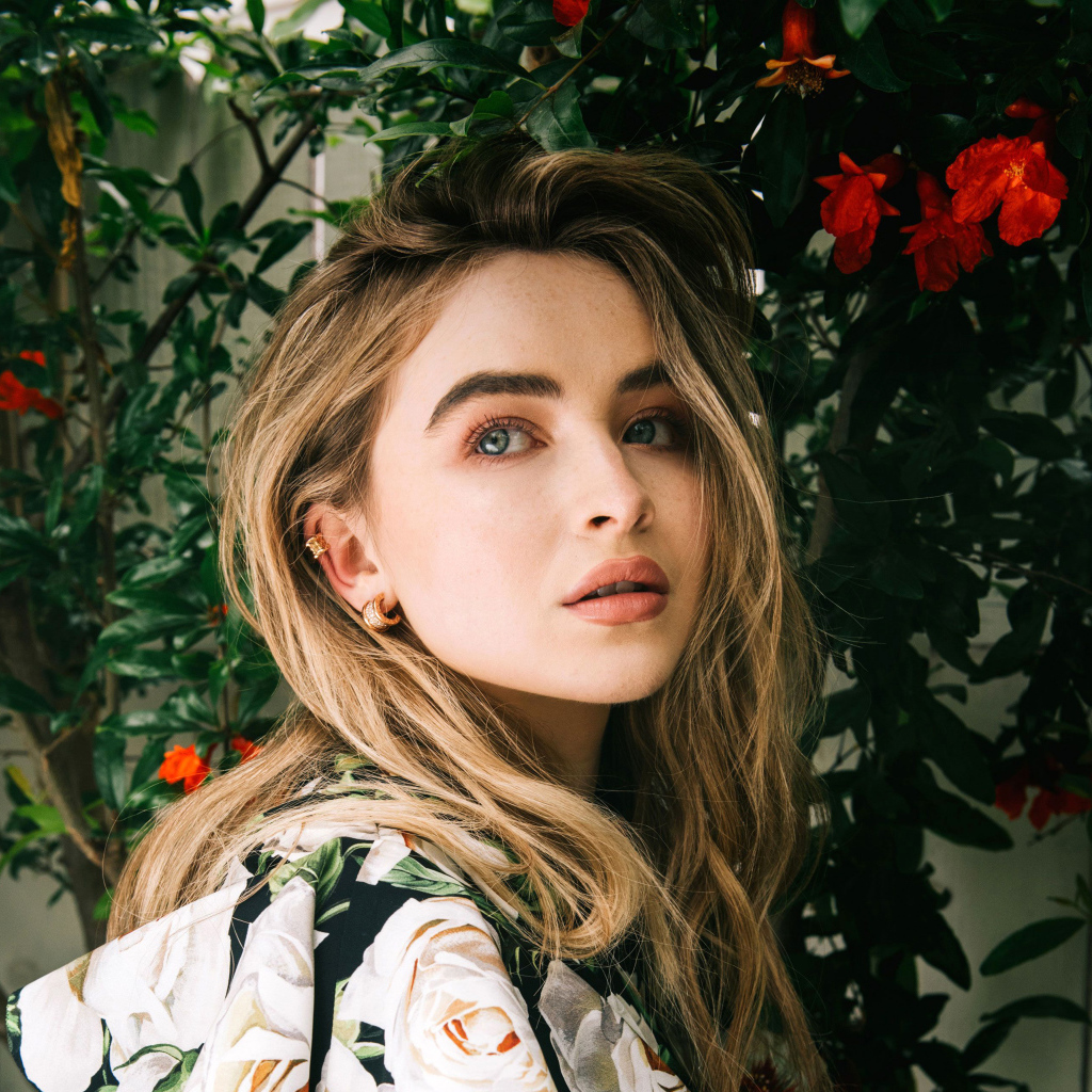 Молодая красивая актриса Сабрина Карпентер у красных цветов