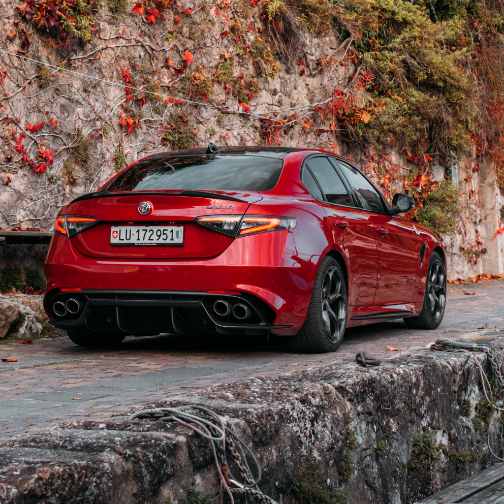 Красный автомобиль Alfa Romeo Giulia Quadrifoglio 2021  года на дороге в горах