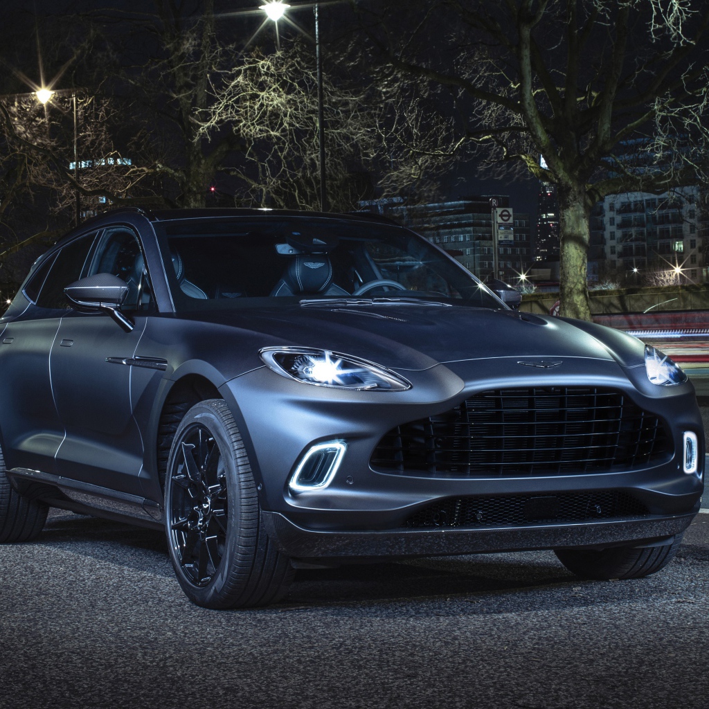 Автомобиль Aston Martin DBX Q Concept 2020 года с включенными фарами вечером