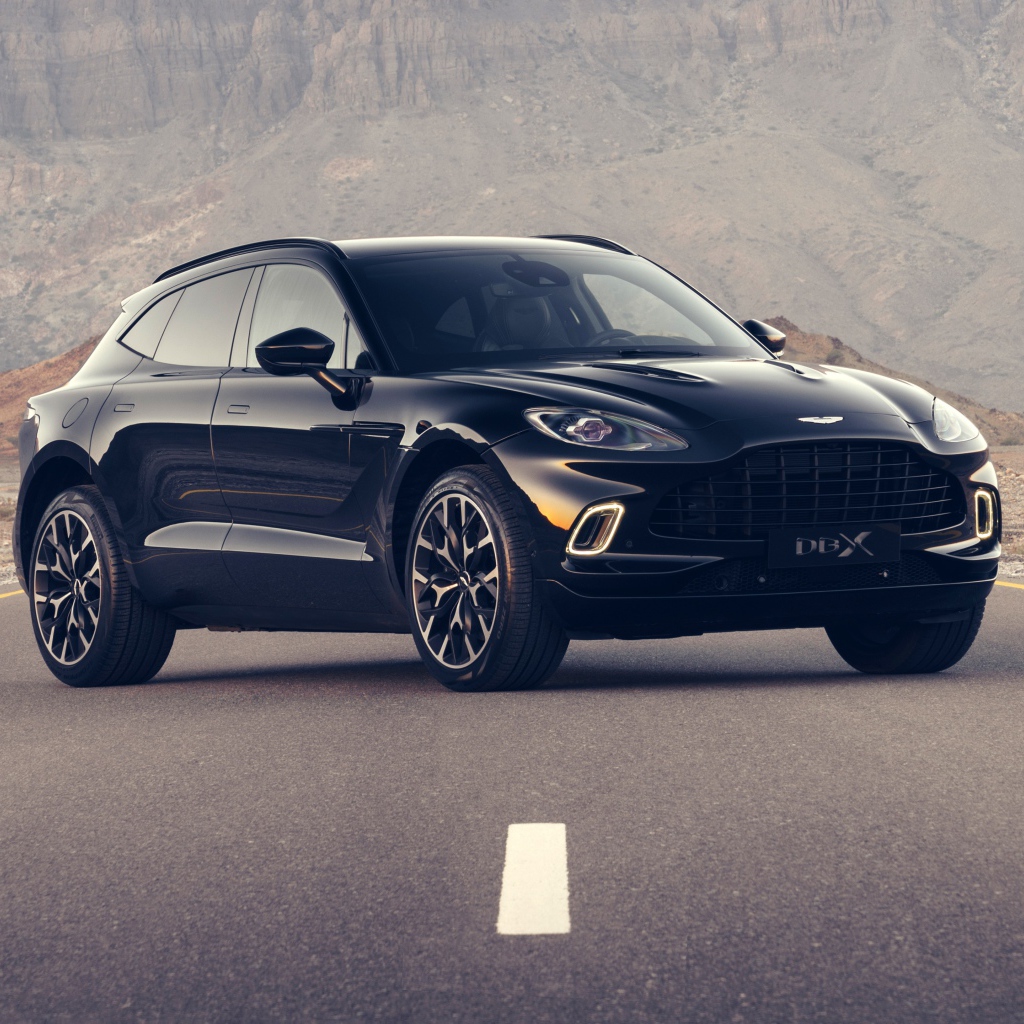 Черный автомобиль aston Martin DBX 2020 года на трассе в горах