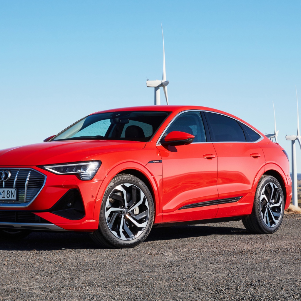 Красный автомобиль Audi E-Tron 50 Quattro Sportback S Line 2020 на фоне ветряных турбин