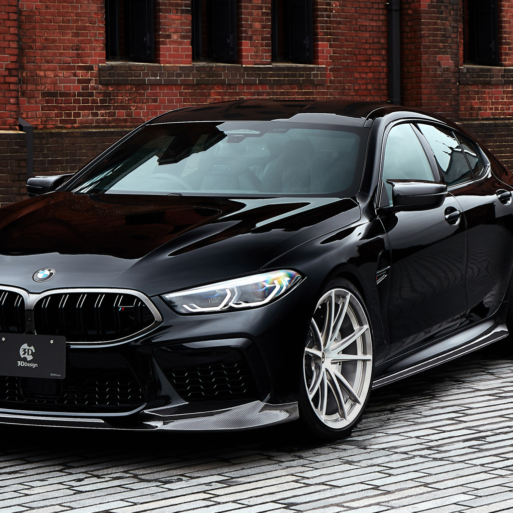 Дорогой черный автомобиль BMW M8 у стены