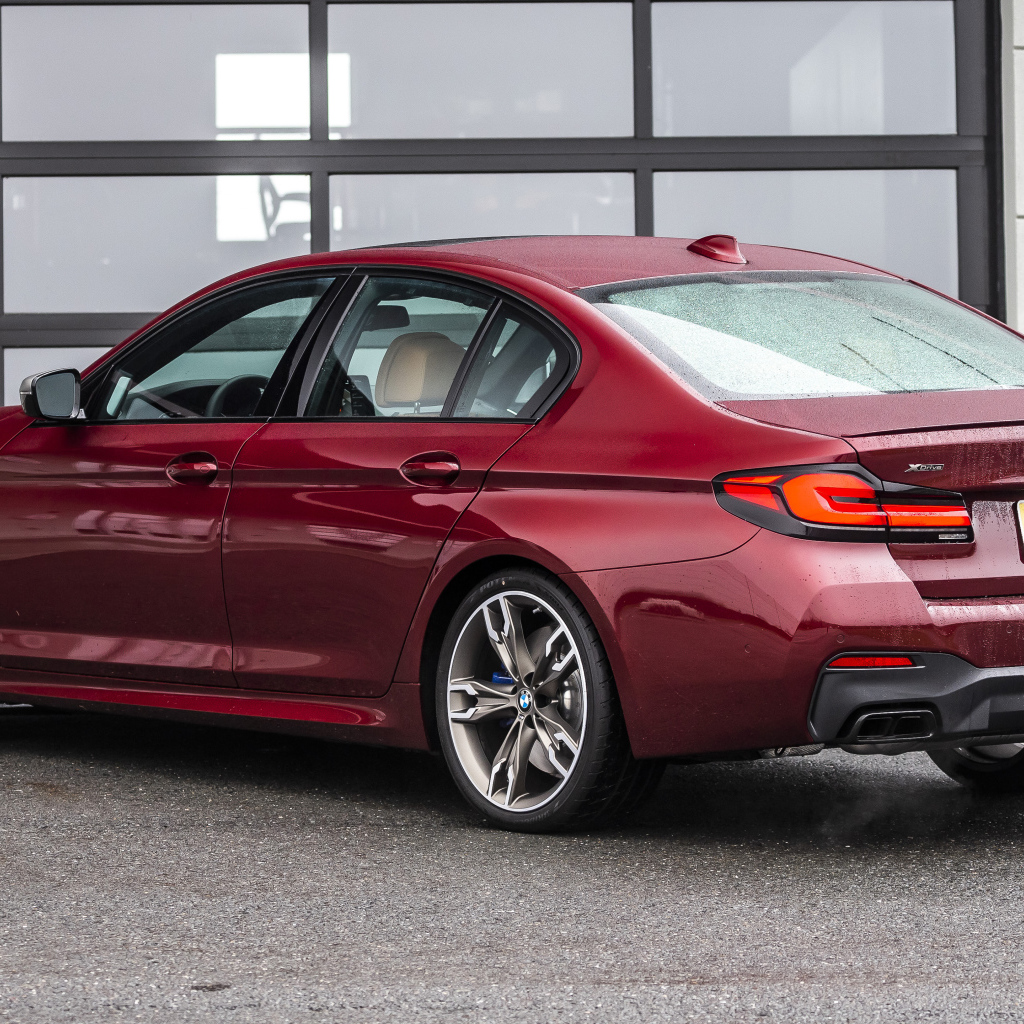 Красный автомобиль BMW M550i XDrive, 2021 года вид сзади
