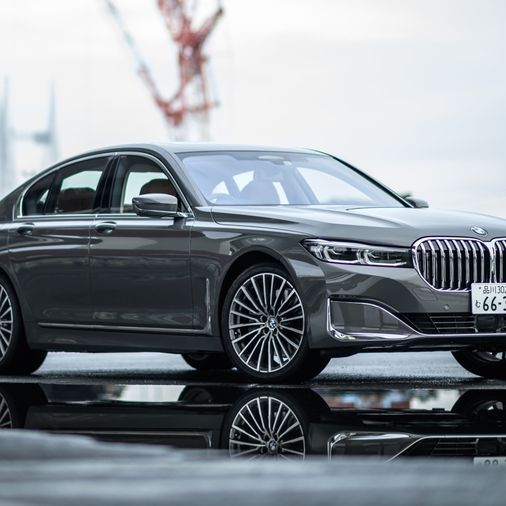 Серебристый автомобиль BMW 745e на мокром асфальте 