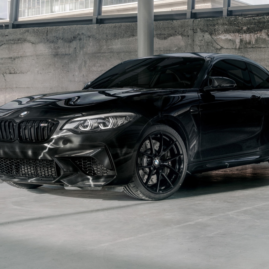 Черный автомобиль  BMW M2, 2020 года у бетонной стены