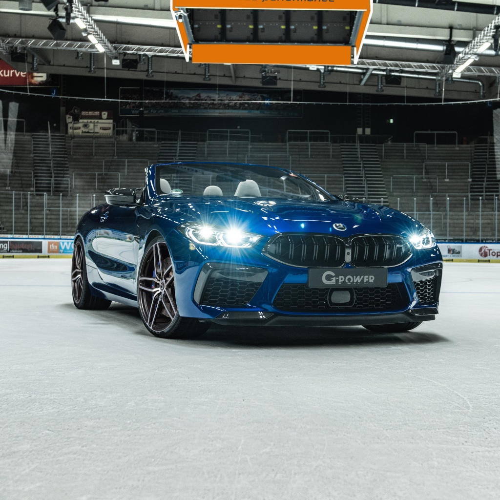 Кабриолет BMW M8,  2020 года с включенными фарами на стадионе 