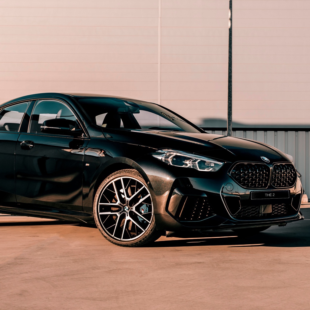 Черный автомобиль BMW M235i XDrive Gran, 2020 года у белого здания 