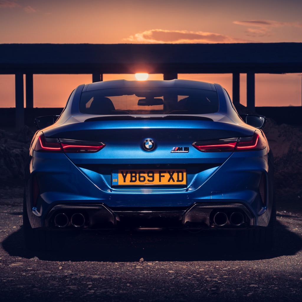 Синий автомобиль BMW M8, 2019 года на фоне заката 
