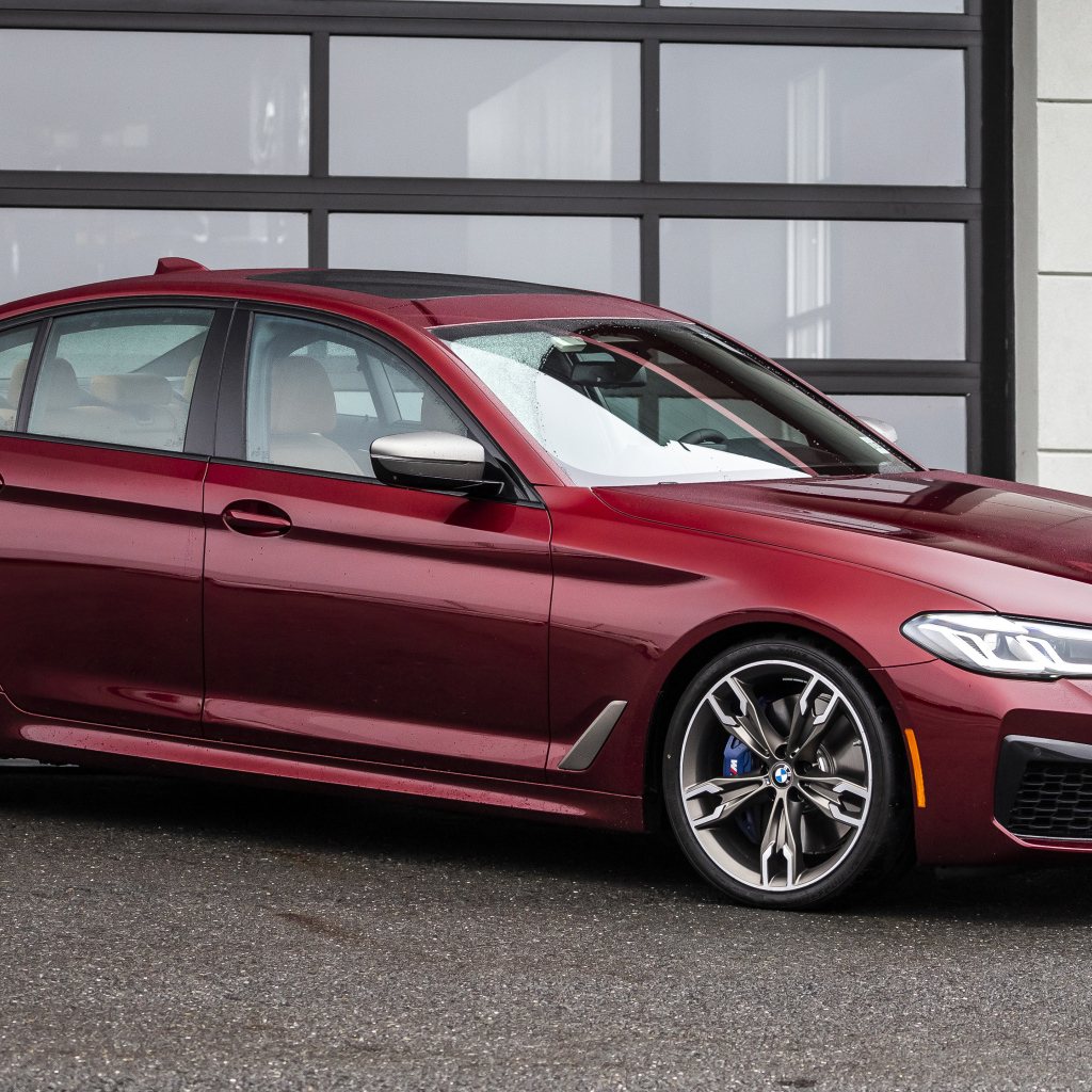 Красный автомобиль BMW M550i XDrive, 2021 года у гаража