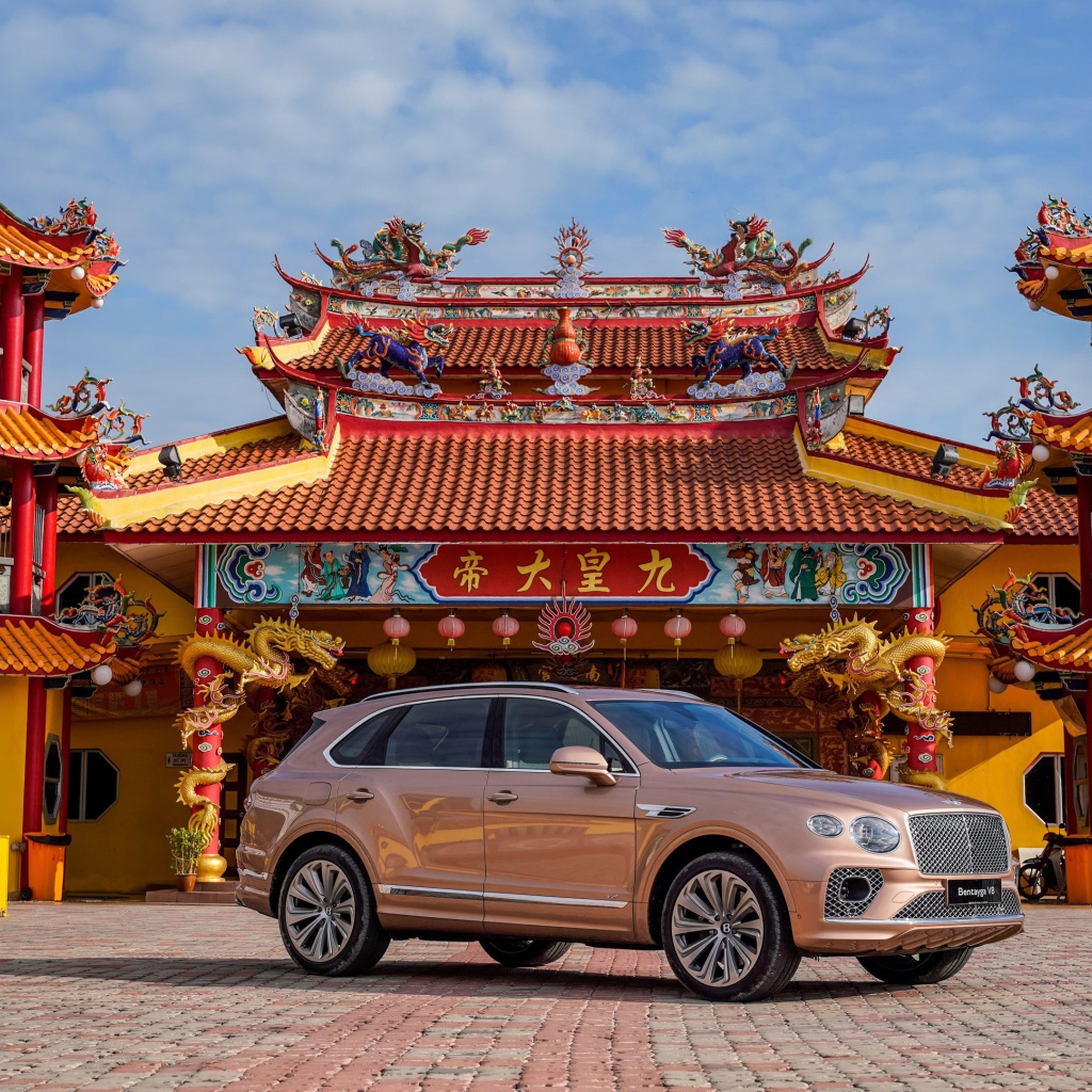 Коричневый автомобиль Bentley Bentayga V8 2020 года на фоне красивого здания