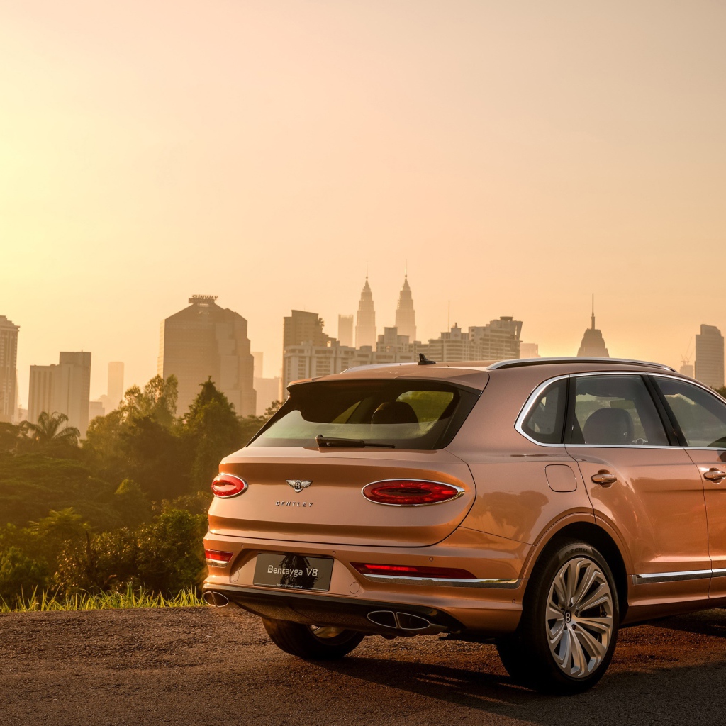 Автомобиль Bentley Bentayga V8 2020 года вид сзади на фоне города 