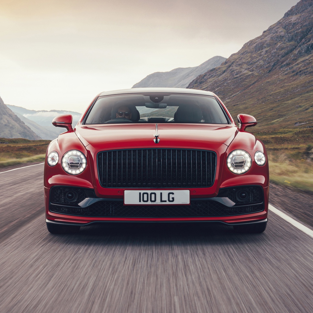 Красный автомобиль Bentley Flying Spur V8 2020 года на дороге в горах 