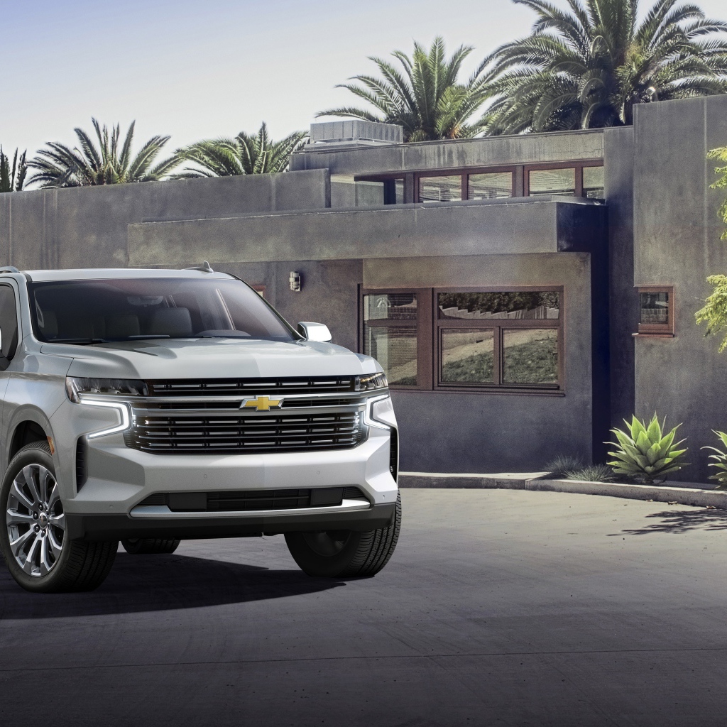 Серый внедорожник Chevrolet Suburban, 2021 года на фоне дома