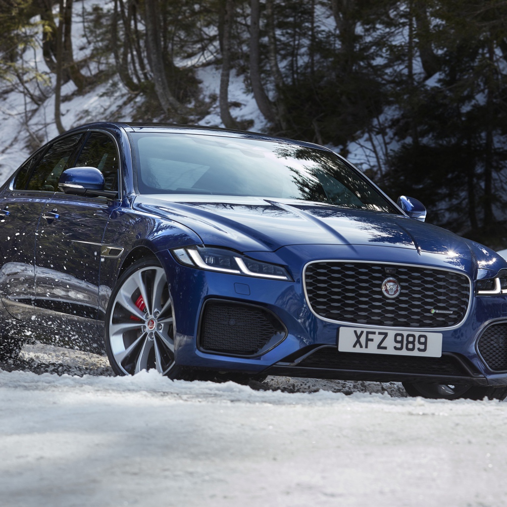 Синий Jaguar XF P300 AWD R-Dynamic 2020 года в заснеженном лесу 