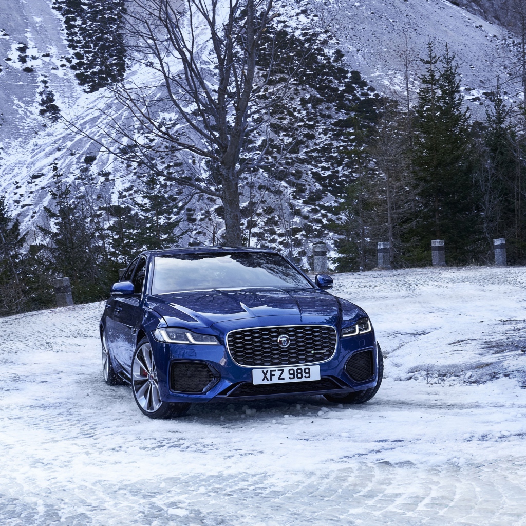 Синий автомобиль Jaguar XF зимой на фоне горы 