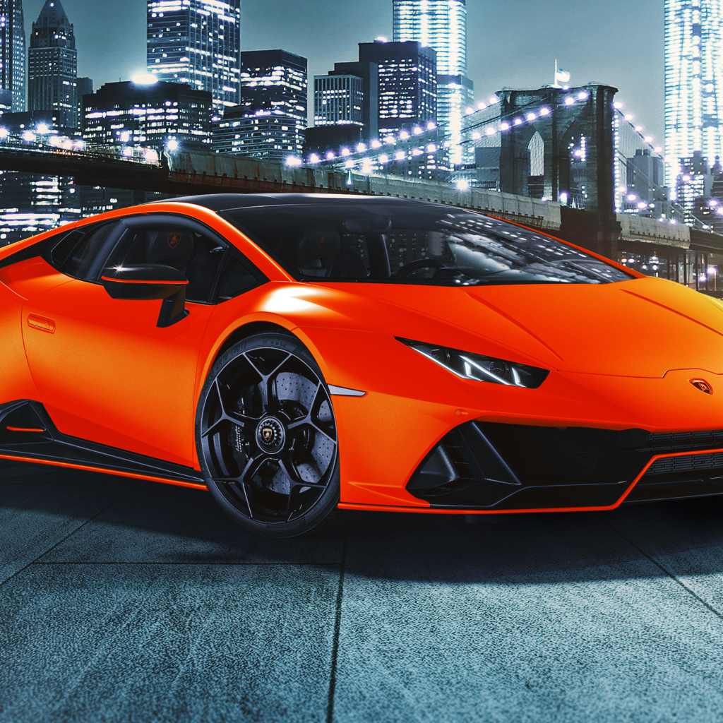 Оранжевый автомобиль Lamborghini Huracán EVO 2021 года на фоне небоскребов
