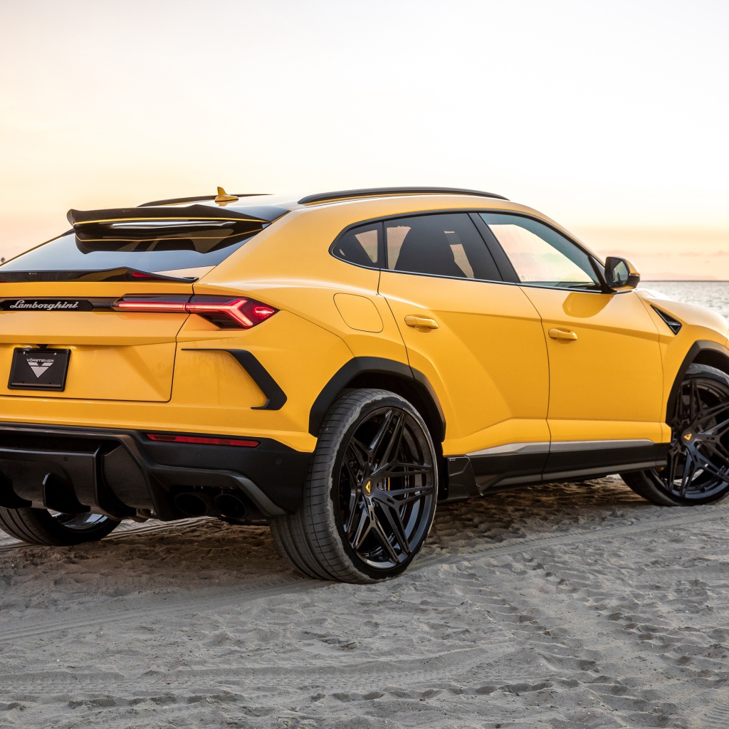 Желтый автомобиль  Lamborghini Urus на песке у моря